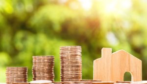 Image of money stacked next to wooden model house