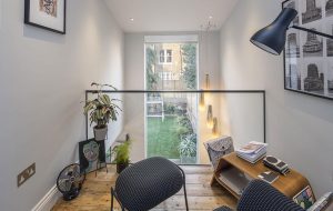 A mezzanine space that is sectioned off with glass. It looks into the back yard