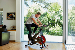 A man wearing a white t-short using an exercise bike