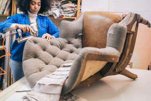 Woman reupholstering old chair with neutral fabric