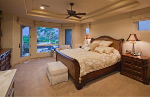 Bedroom with neutral colour palette. The bed is in the middle of the right wall with two bedside tables.