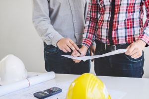Two people looking at a schematic with hardhats in front of them