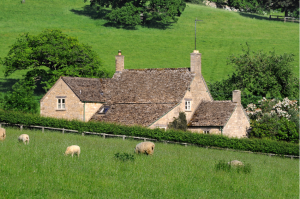 An English farm house with sheep grazing in the field in the foreground