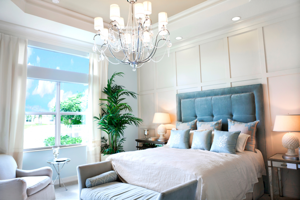 neutral bedroom with blue headboard and chandelier