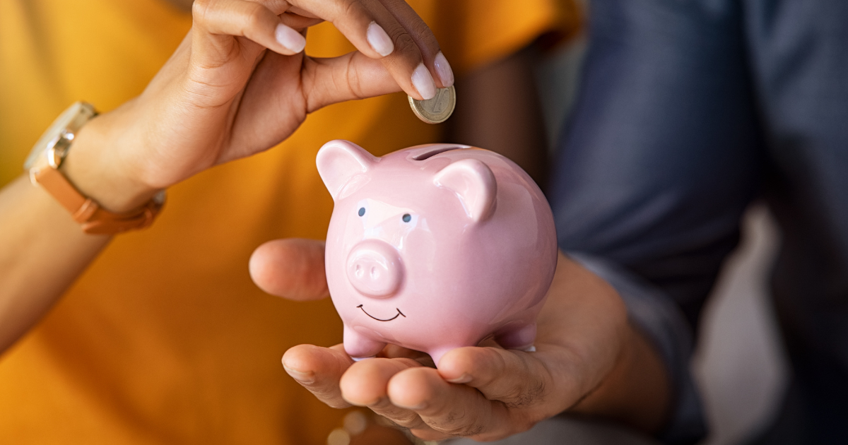 image of a hand putting money into a piggy bank
